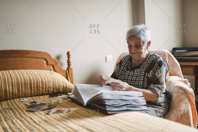 Senior woman looking old photos of her childhood at home