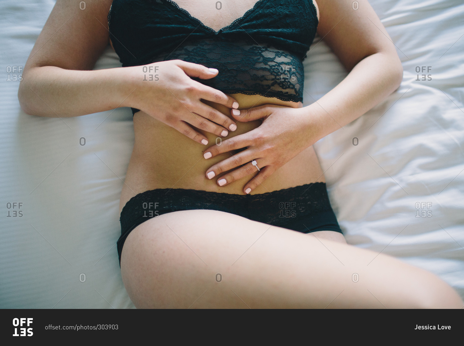 Woman in black underwear lying on bed stock photo - OFFSET