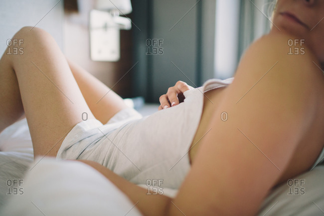 Woman in panties and t-shirt on bed stock photo - OFFSET