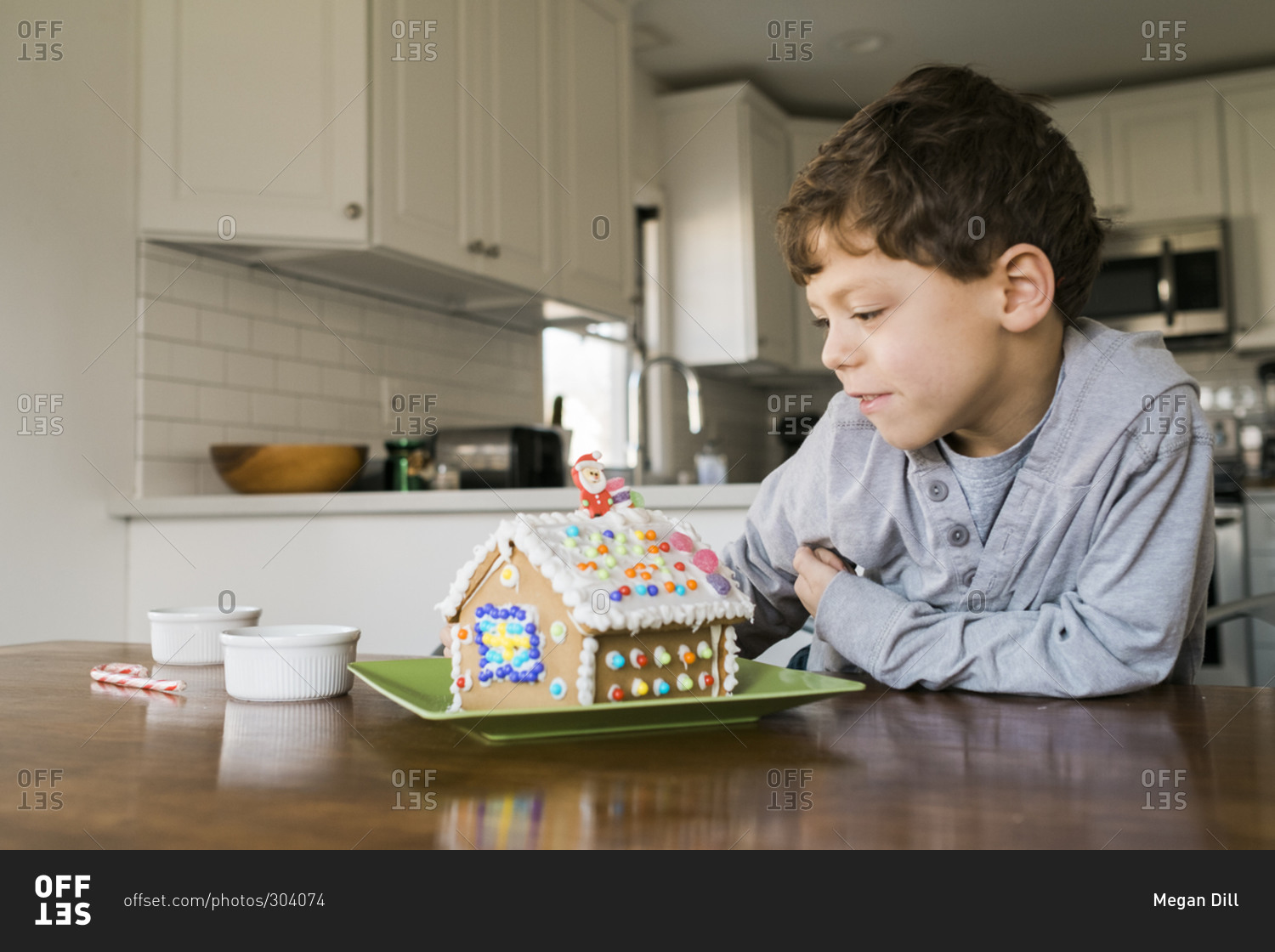 Boy looking at a decorated gingerbread house