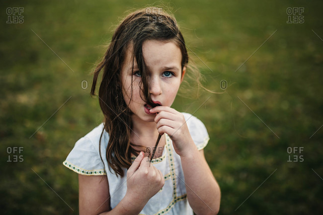Beautiful young girl chewing on her hair stock photo - OFFSET