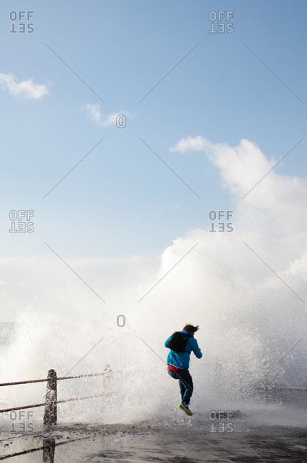 Man jumping on sea front with crashing waves, Sea Point, Cape Town, Western Cape, South Africa