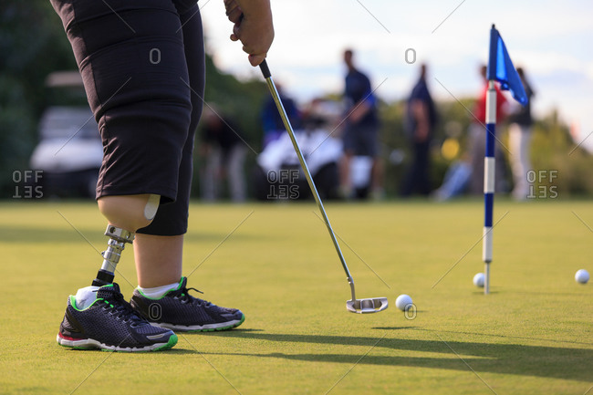 Woman with prosthetic leg at golf putting green