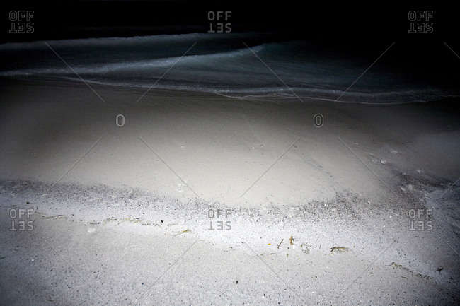 Sand and surf on a beach at night