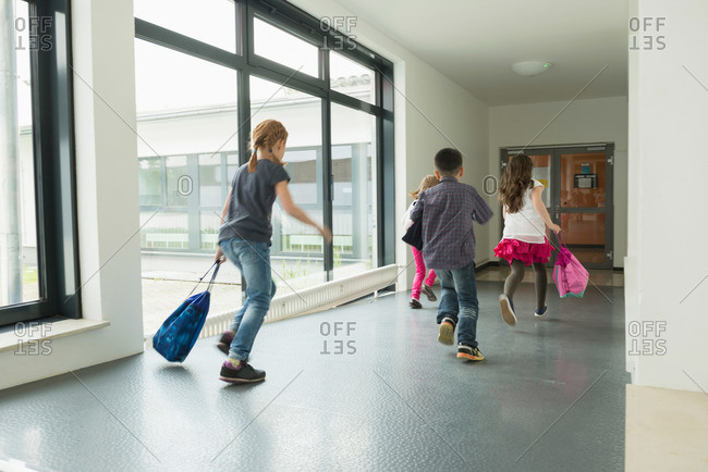 Children running with sports bags in corridor of sports hall, Munich, Bavaria, Germany
