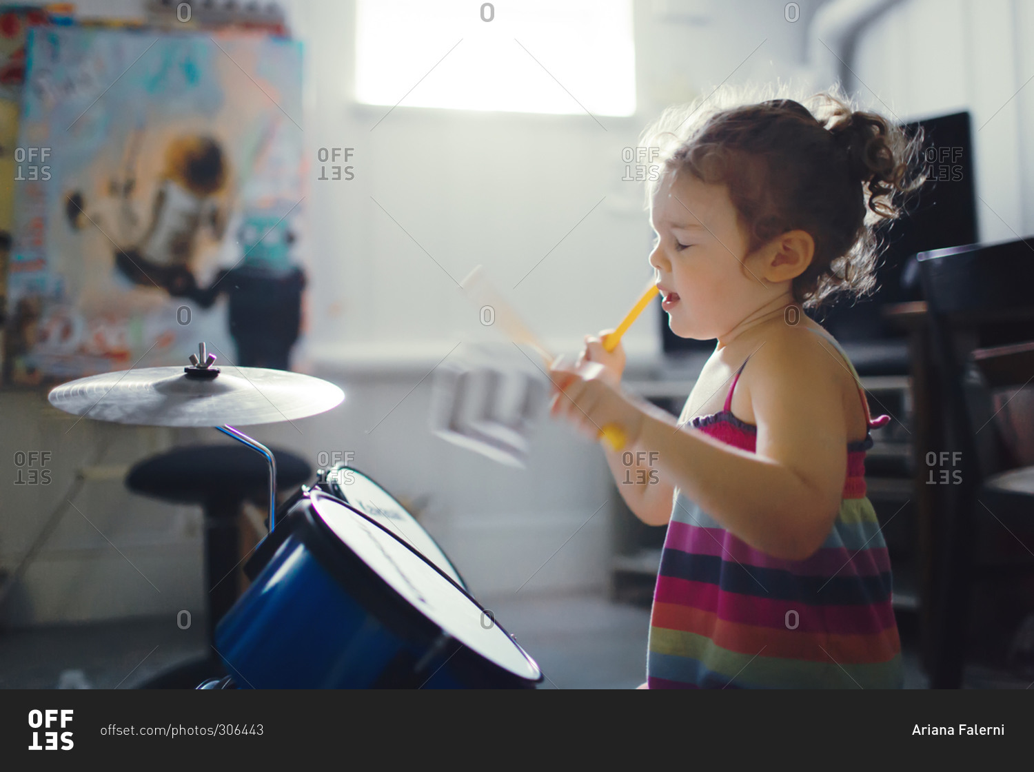 Little girl playing the drums stock photo OFFSET