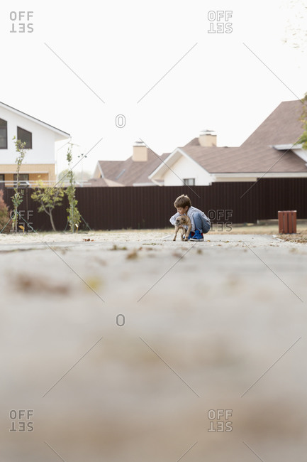 Boy playing with dog on footpath against clear sky