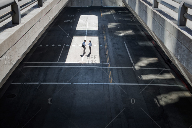 View from above onto a city plaza and two men walking from shadow into sunlight