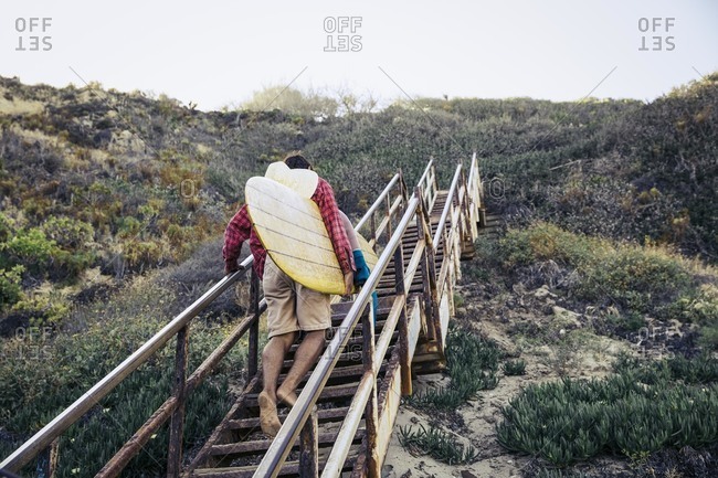 Man climbing up steps with surfboard