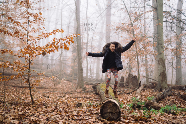 Girl balancing on log in misty woods