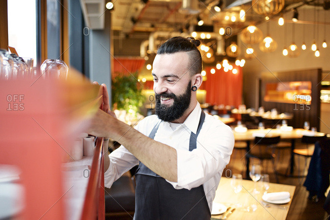Waiter getting a roll of receipt paper from a shelf