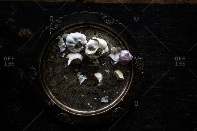 Garlic on antique platter on dark wooden table