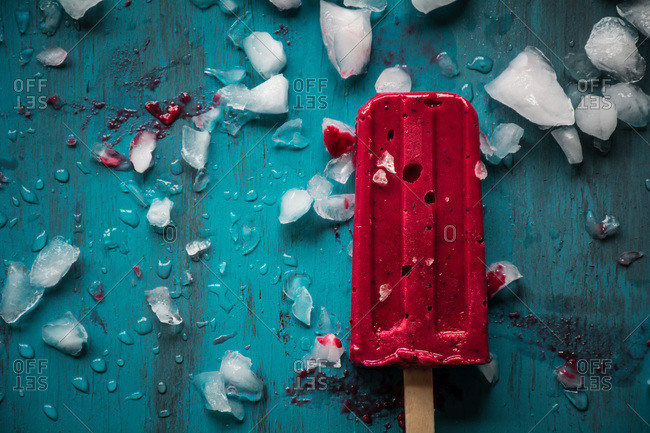 Red popsicle with ice on blue table
