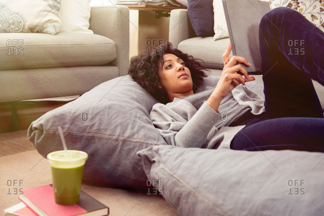 Woman lying on cushions with tablet