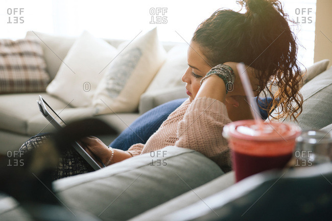 Woman resting on couch with tablet