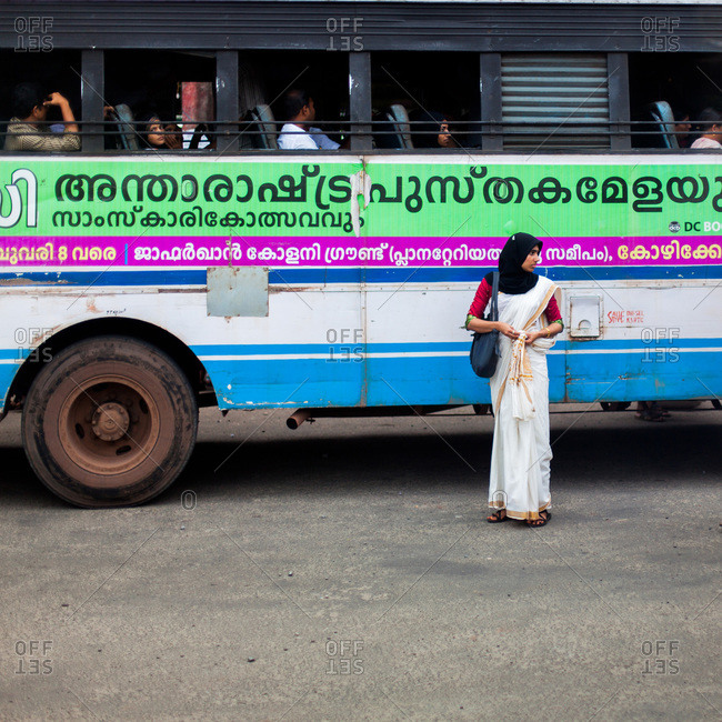 Kerala, India - September 11, 2013: Woman standing in front of a bus in the streets of Kerala, India