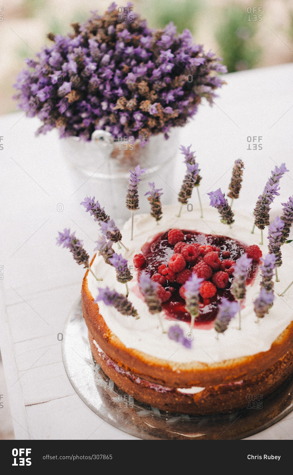 Cake topped with raspberries and purple flowers
