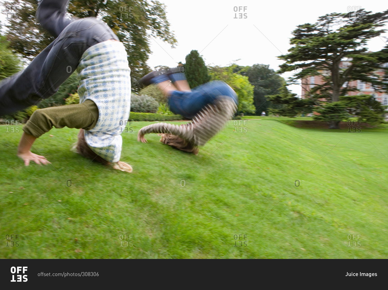 Boy and girl rolling down hill stock photo - OFFSET