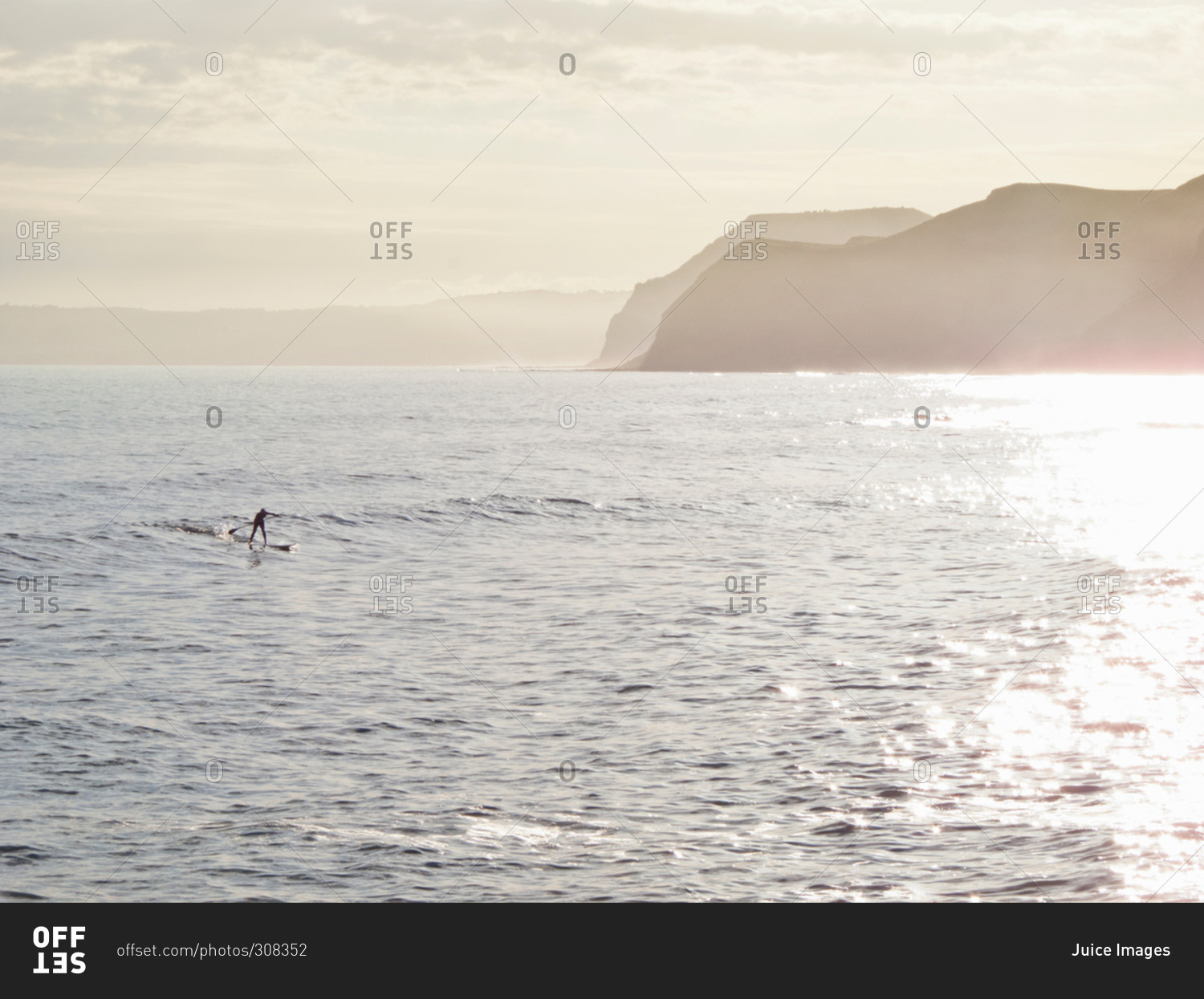 Man riding a wave whilst paddle surfing in picturesque location