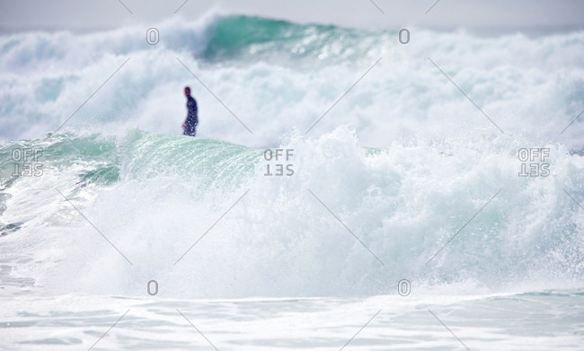 Distant surfer standing on surfboard