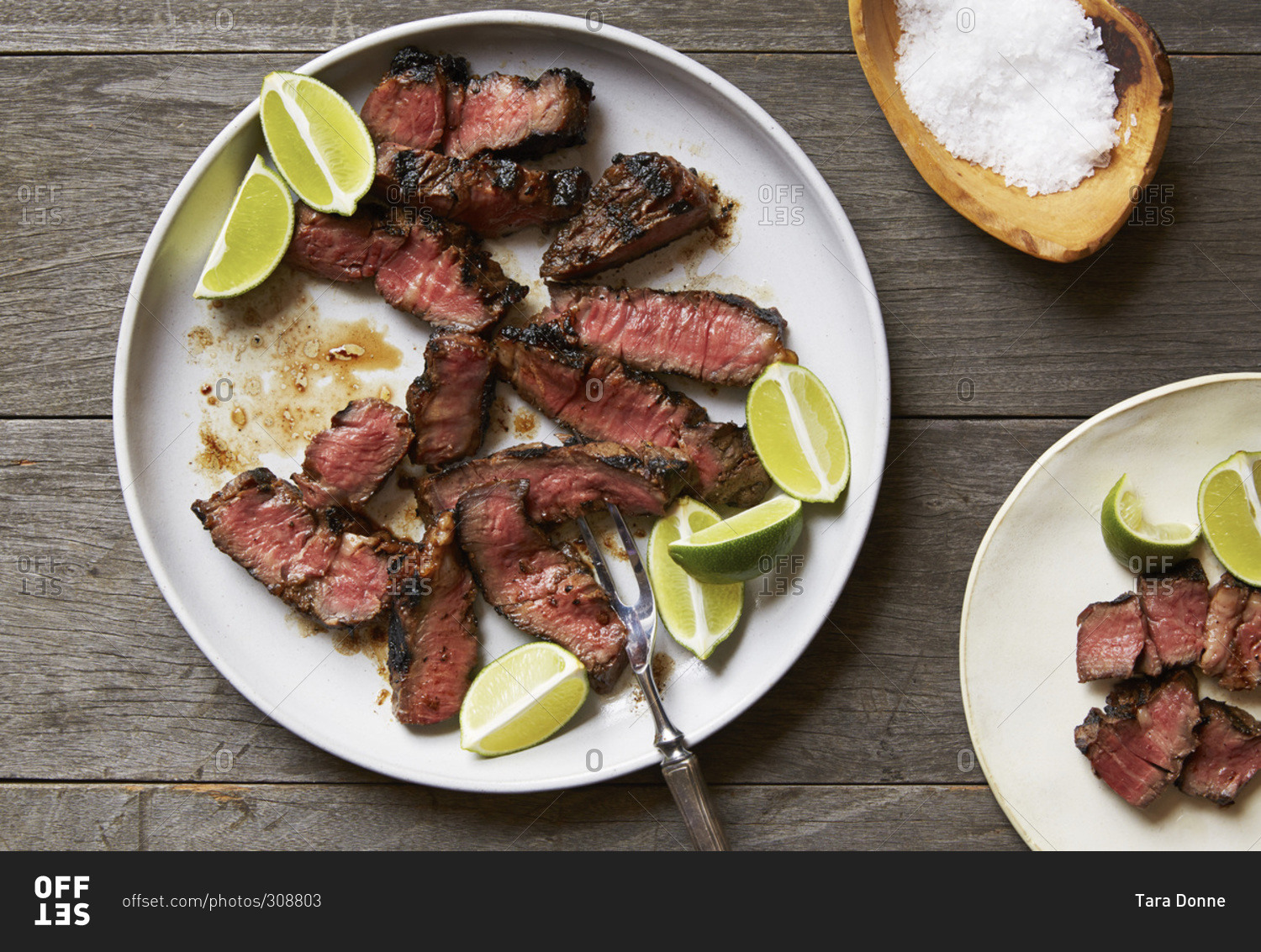 Sliced grilled steak with lime wedges