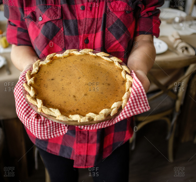Woman holding baked pumpkin pie for Thanksgiving
