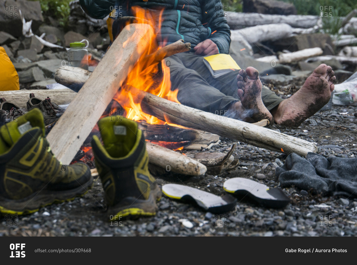 Man drying shoes and feet by fire in Aniakchak, AK