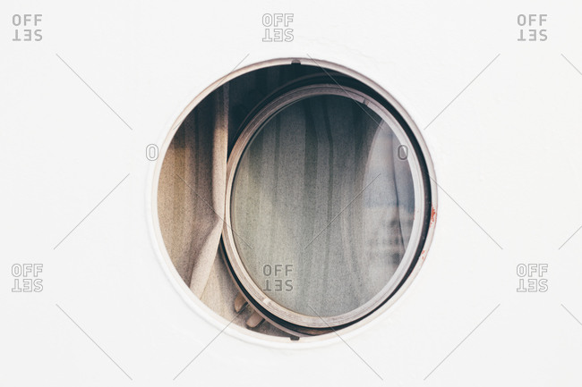 Open round window on the side of a cruise ship