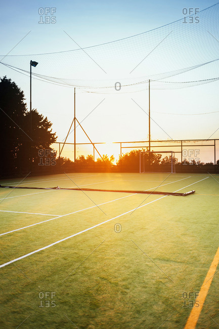 Empty tennis court at sunset with the net down