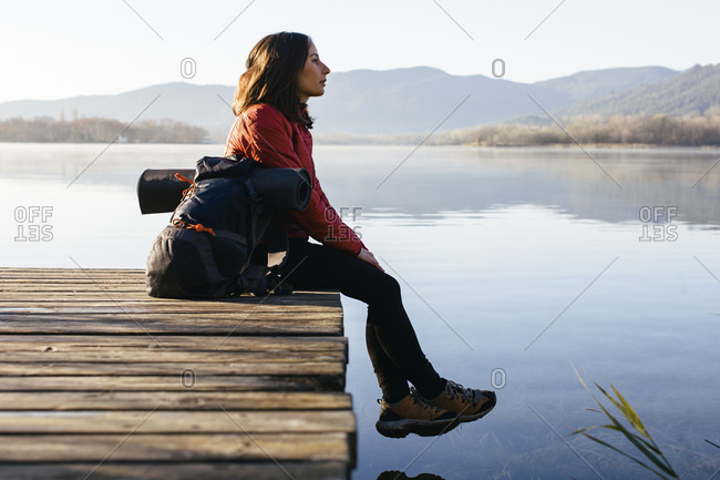Spain, Catalunya, Girona, female hiker resting on jetty at a lake enjoying the nature