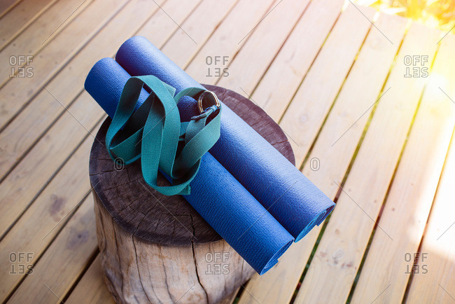Yoga mats and strap on a wooden log