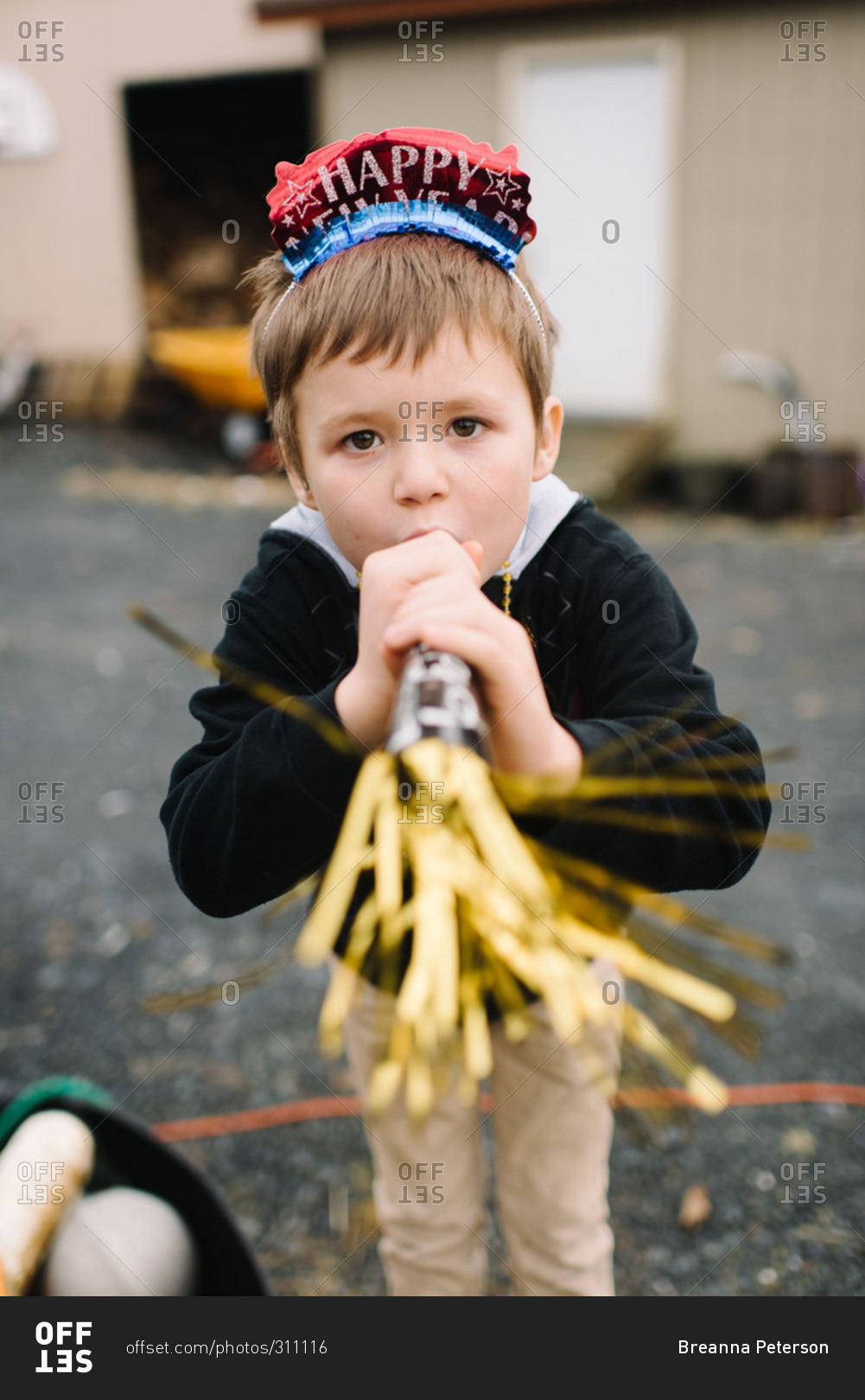 Boy in New Year's headband blowing party horn