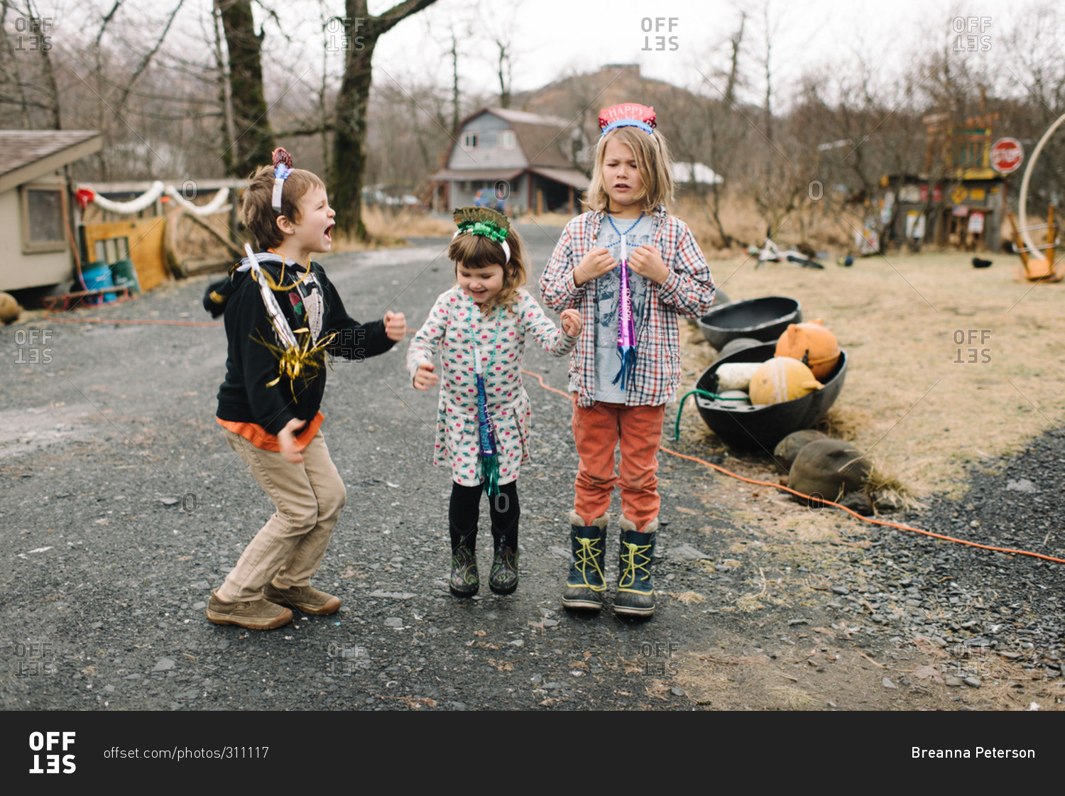 Three children play outdoors with New Year's party gear