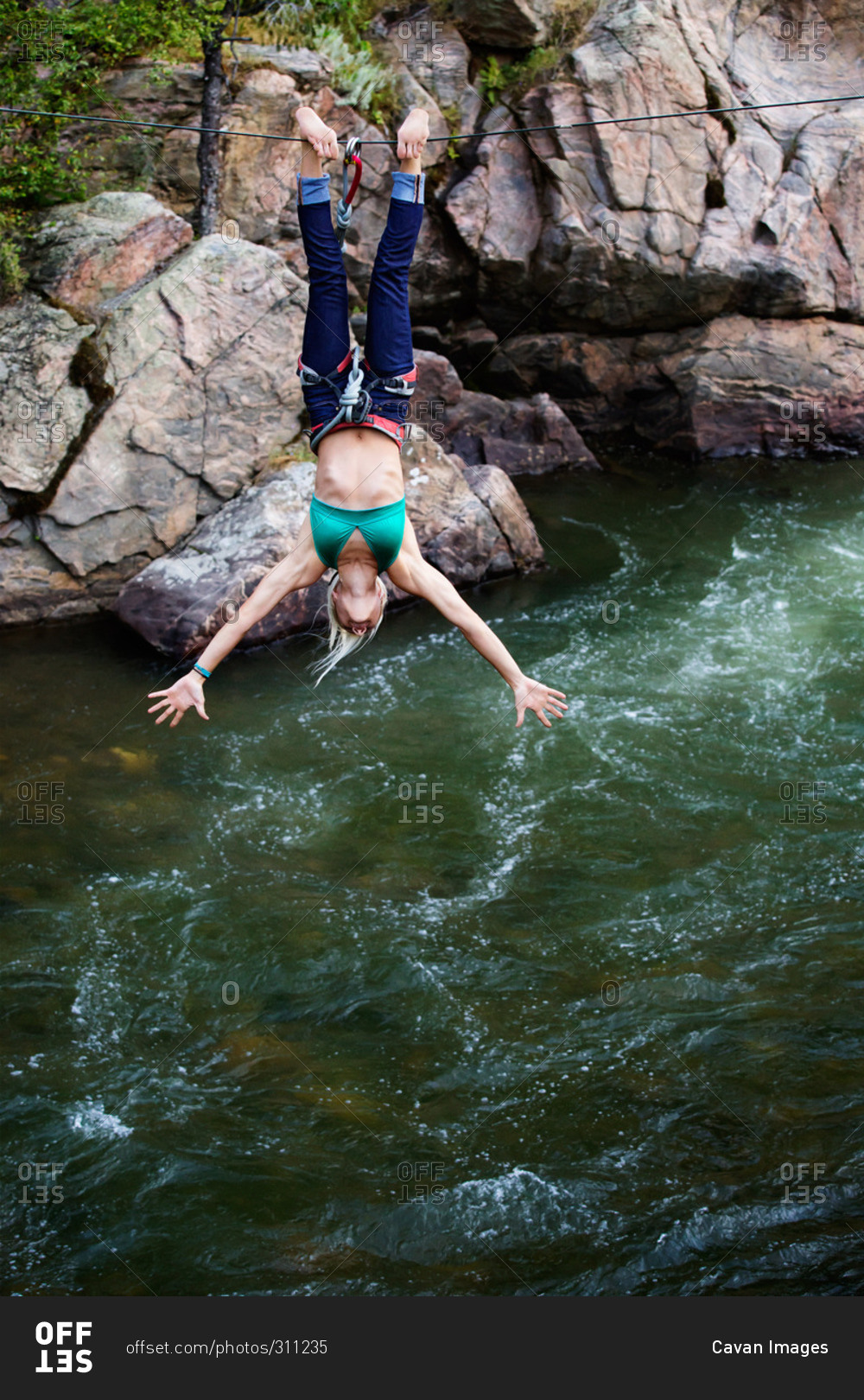 Athletic woman doing tricks from a rope over a river