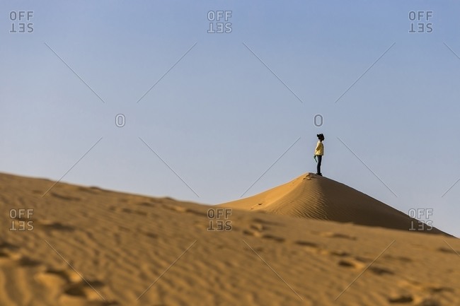Tindouf, Algeria - February 26, 2015: A young girl looking at the horizon from above a sand dune