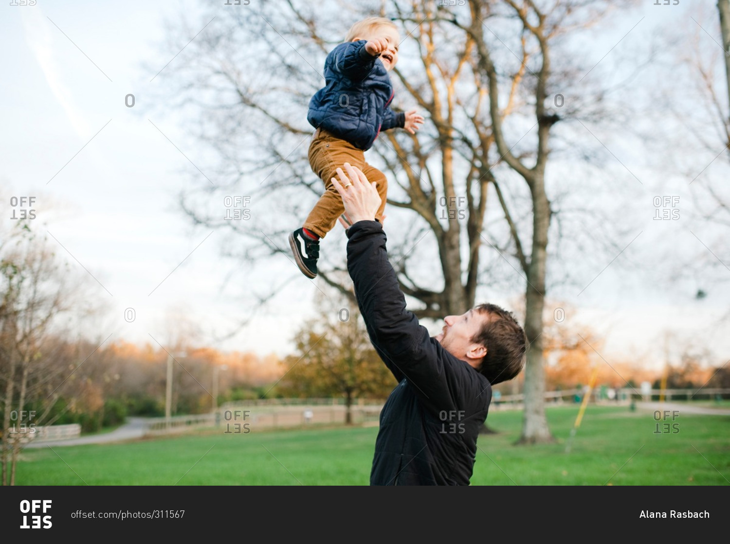 Father throwing toddler boy into the air stock photo OFFSET