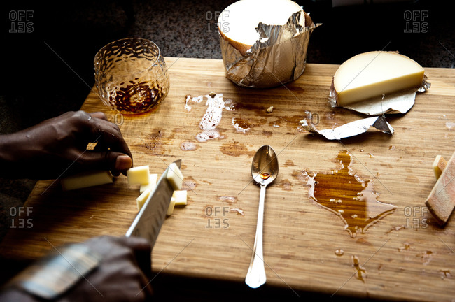 Chef slicing pieces of cheese on wooden cutting board