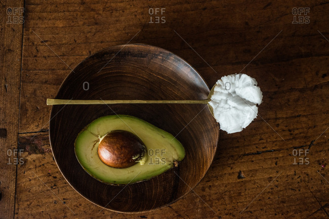 Avocado in bowl and spoonful of coconut oil