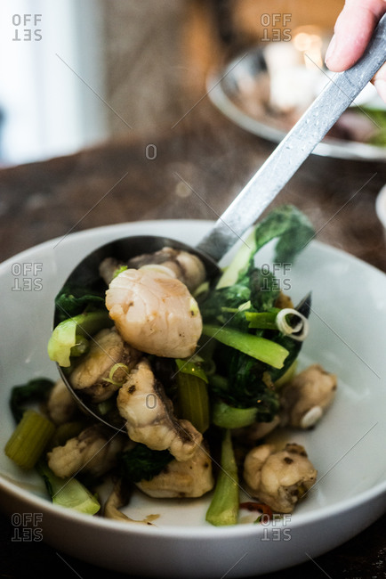 Spooning seafood stew into bowl