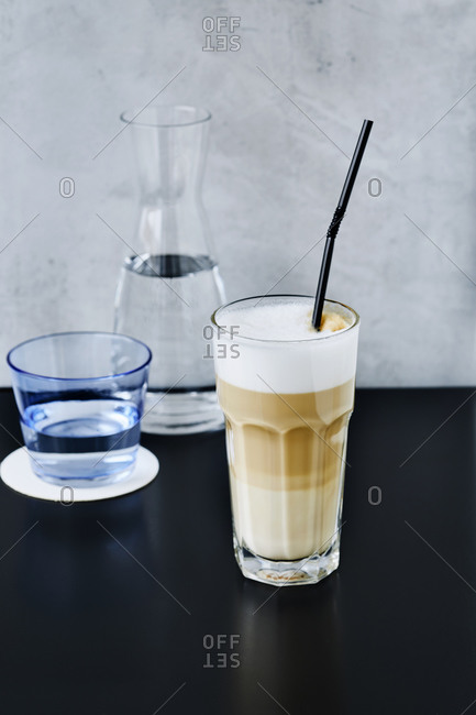 Cafe latte with straw in glass on Cafe table
