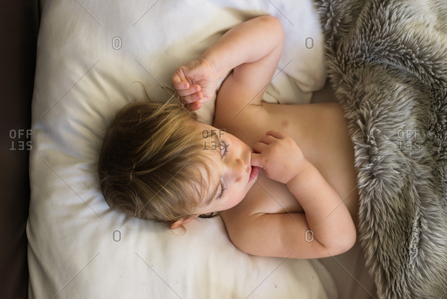 Little girl lying in bed under a furry blanket