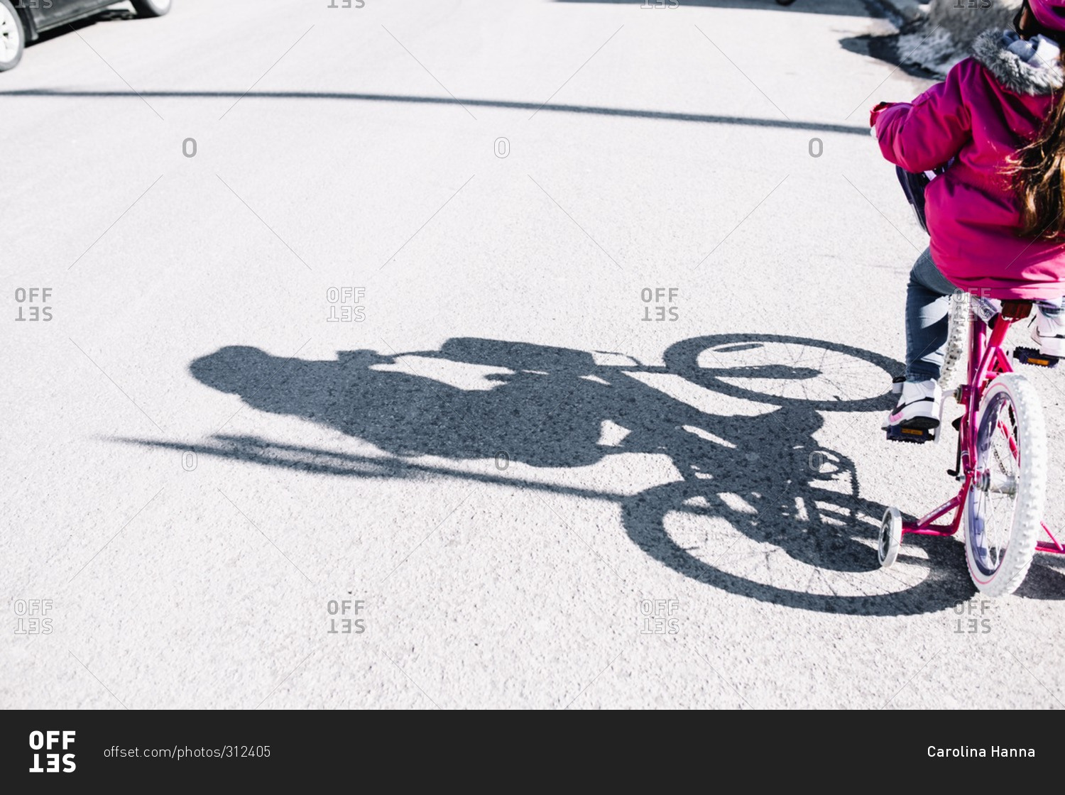 Shadow of young girl riding a bike with training wheels