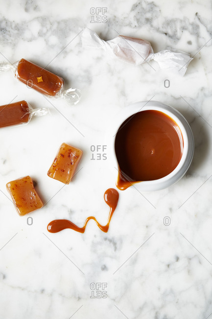 Caramel candies by a bowl of melted caramel sauce