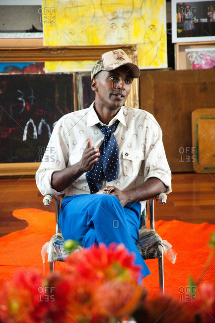 New York City - August 21, 2012: Chef Marcus Samuelsson sitting in chair surrounded by paintings in his colorful living room