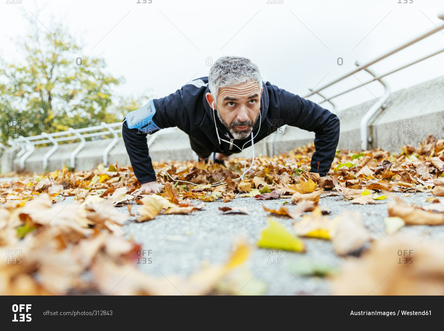 Man doing pushups surrounded by autumn leaves