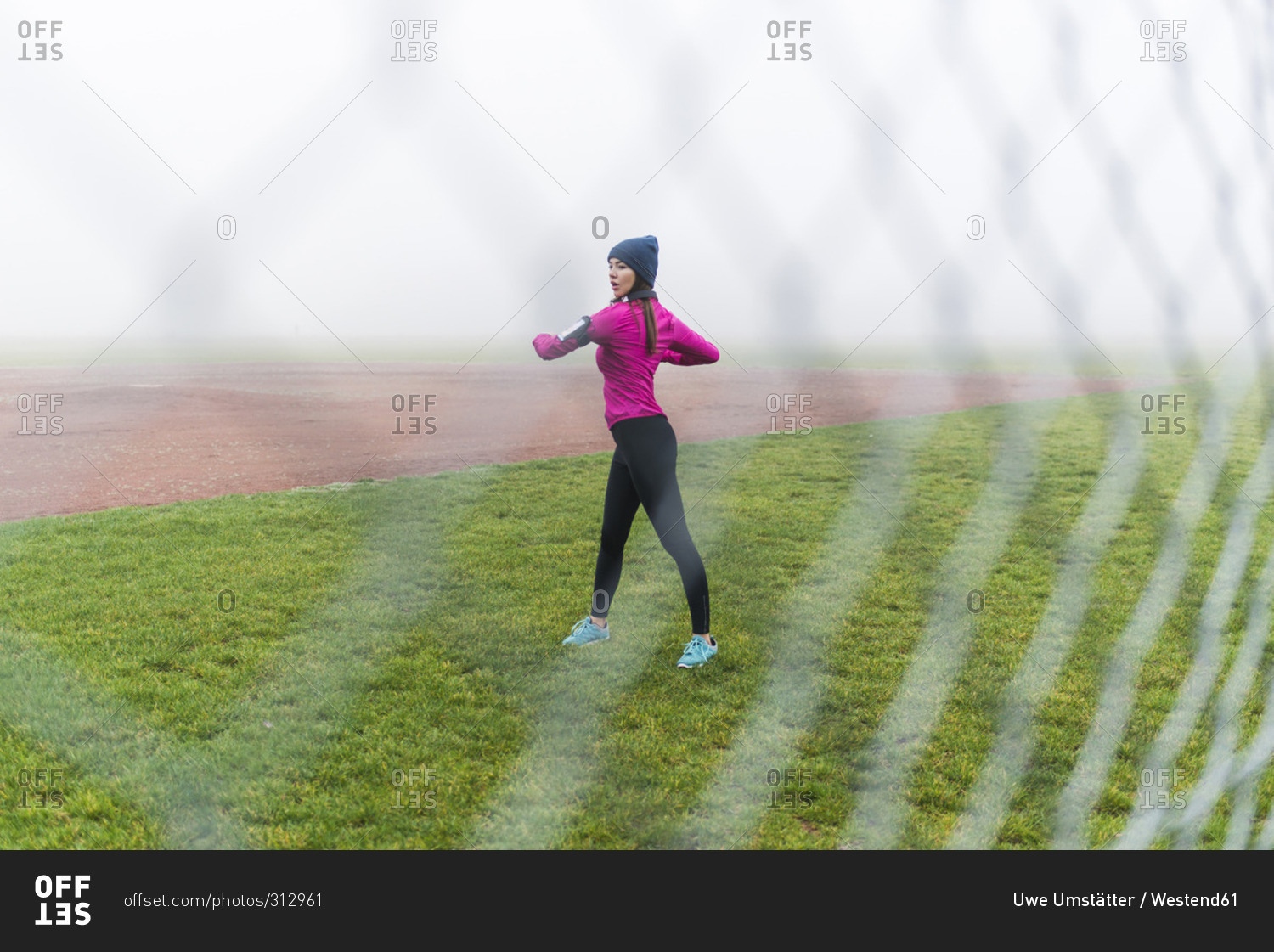 Young woman doing workout on a grass behind mesh wire fence