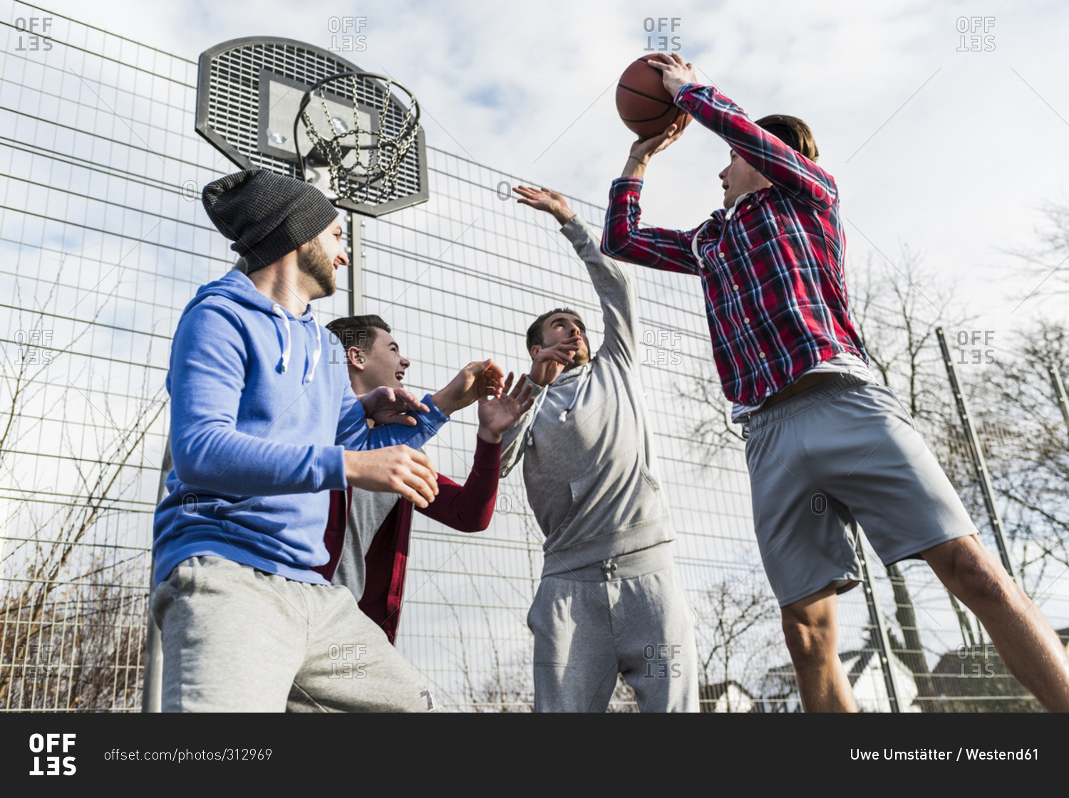 Young men playing a pick up game of basketball stock photo OFFSET