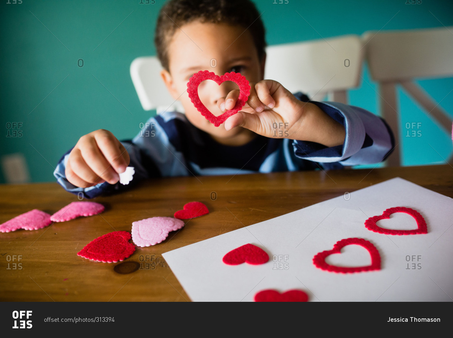 Little boy holding heart while making a Valentine's Day craft