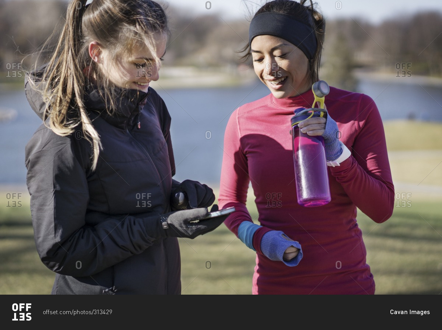 Two women in workout gear looking at smartphone together