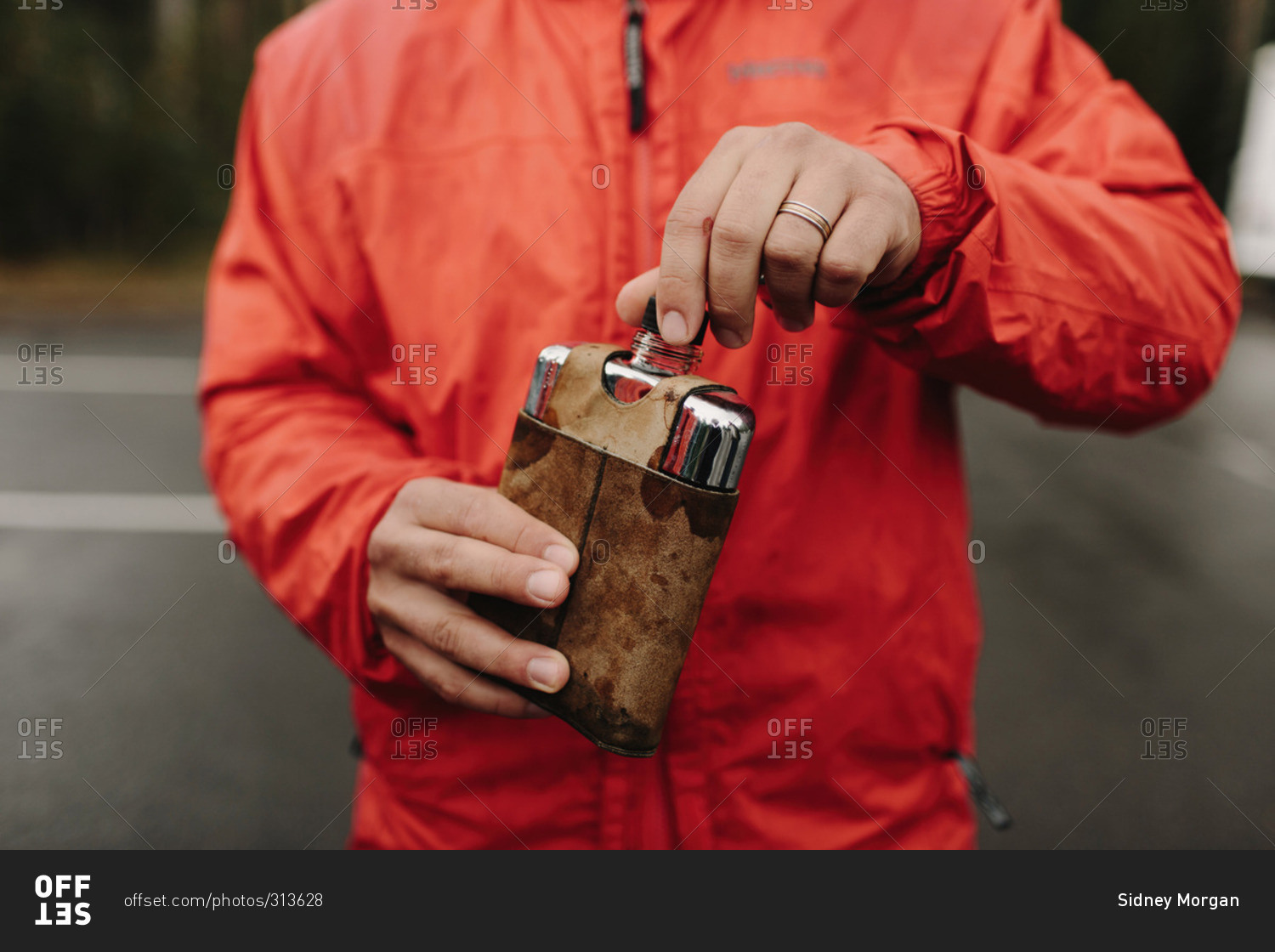 Man in rain coat holding flask